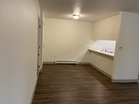 an empty kitchen with wood flooring and white walls